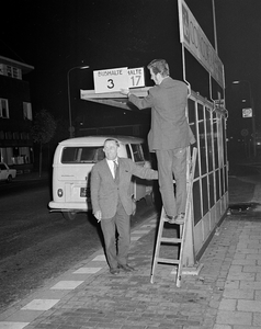 855109 Afbeelding van het verwisselen van een bord op een abri voor stadsbussen in de wijk Zuilen te Utrecht. Per 24 ...